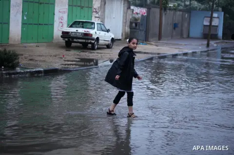 Palestinian students walk in a flooded street during a rainy day in Khan Younis in the southern Gaza Strip October 7, 2015. Photo by Ashraf Amra