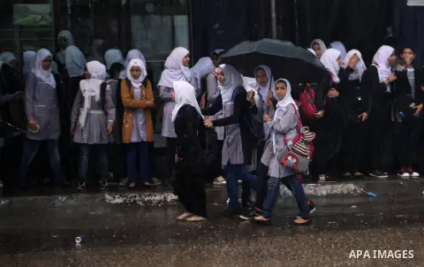 Palestinian schoolgirls stand as they go to school on a rainy day in Khan Younis in the southern Gaza Strip October 7, 2015. Photo by Ashraf Amra