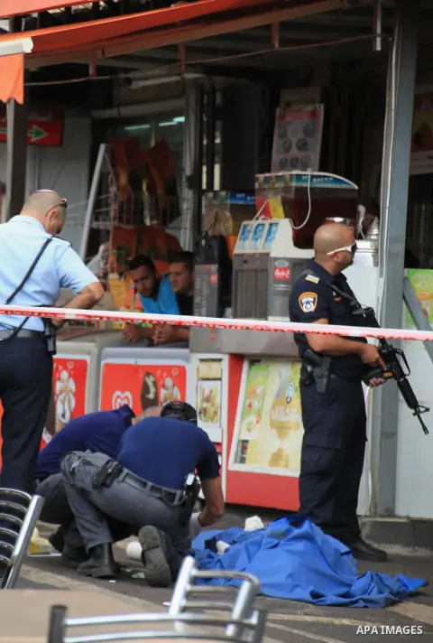 Israeli police secure the area as they stand next to the body of a dead Palestinian assailant at the spot where he stabbed two Israeli Jews before was shot dead outside Jerusalem's Old City October 10, 2015. Israeli forc...