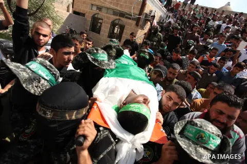 Palestinian militants of the Ezzedine al-Qassam Brigades, Hamas' armed wing, carry the body of Palestinian protester 22-year-old Jihad al-Obeid, who died in clashes with Israeli security forces near the border, during hi...