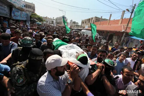Palestinian militants of the Ezzedine al-Qassam Brigades, Hamas' armed wing, carry the body of Palestinian protester 22-year-old Jihad al-Obeid, who died in clashes with Israeli security forces near the border, during hi...