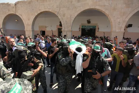 Palestinian militants of the Ezzedine al-Qassam Brigades, Hamas' armed wing, carry the body of Palestinian protester 22-year-old Jihad al-Obeid, who died in clashes with Israeli security forces near the border, during hi...