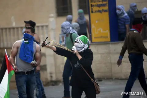 Palestinian protesters hurl stones during clashes with Israeli security forces in Beit El on the outskirts of the West Bank city of Ramallah, on October 10, 2015. Fifteen Palestinians have been killed by Israeli forces a...