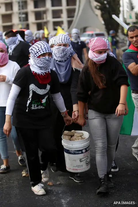 Palestinian girls carry stones during clashes with Israeli security forces in Beit El on the outskirts of the West Bank city of Ramallah, on October 10, 2015. Fifteen Palestinians have been killed by Israeli forces and a...