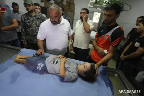 People stand around the body of a three-year-old Palestinian girl who was killed after her house was brought down by an Israeli air strike in Gaza early on October 11, 2015. An Israeli air strike on a Hamas target in the...