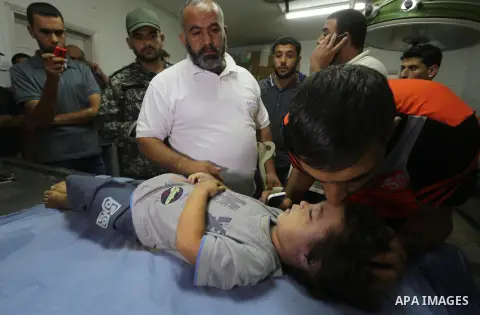 People stand around the body of a three-year-old Palestinian girl who was killed after her house was brought down by an Israeli air strike in Gaza early on October 11, 2015. An Israeli air strike on a Hamas target in the...