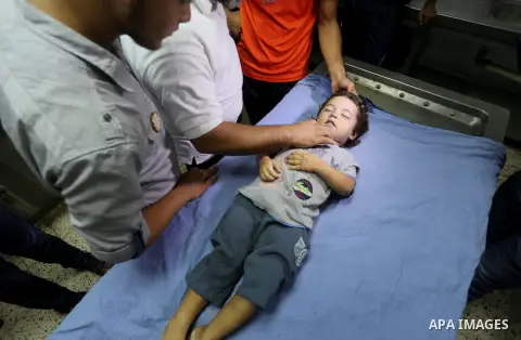 People stand around the body of a three-year-old Palestinian girl who was killed after her house was brought down by an Israeli air strike in Gaza early on October 11, 2015. An Israeli air strike on a Hamas target in the...