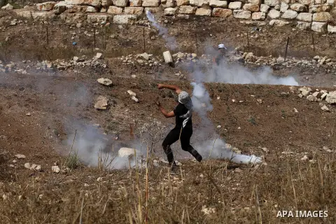 A Palestinian protester throws back a tear gas canister fired by Israeli security forces during clashes at the Hawara checkpoint, south of the West Bank city of Nablus, on October 11, 2015. An Israeli air strike in Gaza...