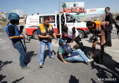 Medics help an injured Palestinian cameraman during clashes with Israeli security forces at the Hawara checkpoint, south of the West Bank city of Nablus, on October 11, 2015. An Israeli air strike in Gaza killed a pregna...