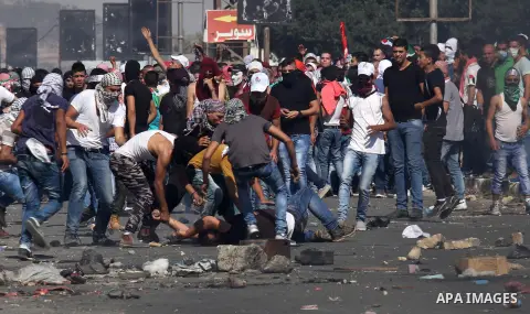 Masked Palestinian protestors help an injured comrade during clashes with Israeli security forces at the Hawara checkpoint, south of the West Bank city of Nablus, on October 11, 2015. An Israeli air strike in Gaza killed...