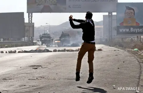 A Palestinian protester throws stones towards Israeli security forces during clashes at the Hawara checkpoint, south of the West Bank city of Nablus, on October 11, 2015. An Israeli air strike in Gaza killed a pregnant w...
