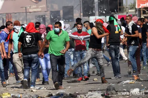 Palestinian protesters throw stones towards Israeli security forces during clashes at the Hawara checkpoint, south of the West Bank city of Nablus, on October 11, 2015. An Israeli air strike in Gaza killed a pregnant wom...