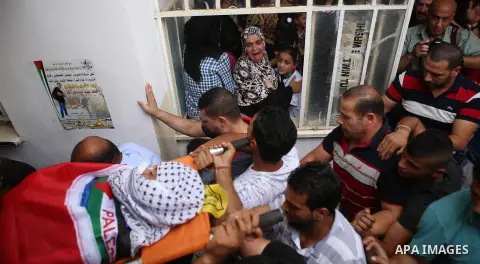 Mourners carry the body of 13-year-old Palestinian boy Ahmed Sharaka, who was killed by Israeli troops during clashes on Sunday after being hit in the head by a plastic-coated metal bullet, during his funeral in Jalazoun...