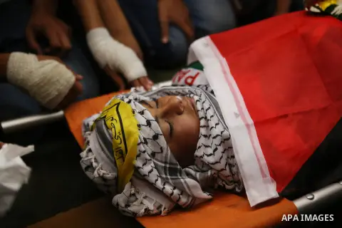 Mourners carry the body of 13-year-old Palestinian boy Ahmed Sharaka, who was killed by Israeli troops during clashes on Sunday after being hit in the head by a plastic-coated metal bullet, during his funeral in Jalazoun...
