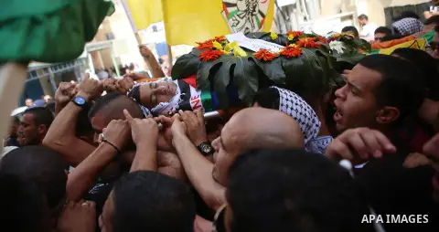 Mourners carry the body of 13-year-old Palestinian boy Ahmed Sharaka, who was killed by Israeli troops during clashes on Sunday after being hit in the head by a plastic-coated metal bullet, during his funeral in Jalazoun...