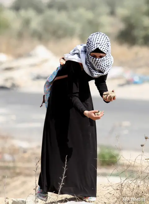 A female Palestinian protester holds stones during clashes with Israeli security forces at the Hawara checkpoint, south of the West Bank city of Nablus, on October 12, 2015. Three new stabbings in Jerusalem and a car att...