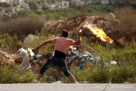 A Palestinian protester throws a molotov cocktail towards Israeli security forces during clashes in Beit El, on the outskirts of the West Bank city of Ramallah, on October 12, 2015. Three new stabbings in Jerusalem and a...