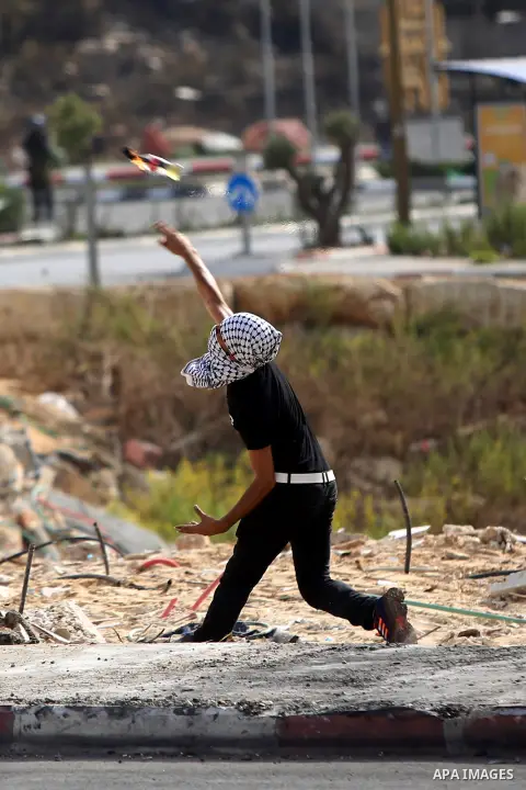 A Palestinian protester throws a molotov cocktail towards Israeli security forces during clashes in Beit El, on the outskirts of the West Bank city of Ramallah, on October 12, 2015. Three new stabbings in Jerusalem and a...