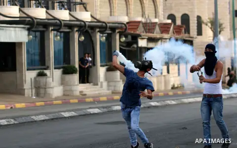 A Palestinian protester throws a tear gas canister back during clashes with Israeli security forces at the main entrance of the West Bank city of Bethlehem, on October 12, 2015. Frustrated Palestinian youths have defied...