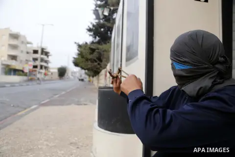A Palestinian protester uses a sling shot to throw stones towards Israeli security forces during clashes at the main entrance of the West Bank city of Bethlehem, on October 12, 2015. Frustrated Palestinian youths have de...