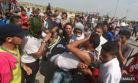 Palestinian protesters carry an injured comrade during clashes with Israeli security forces next to the border fence with Israel, at the Erez crossing in the northern Gaza strip, on October 13, 2015. A wave of stabbings...