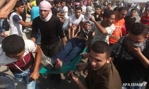 Palestinian protesters carry an injured comrade during clashes with Israeli security forces next to the border fence with Israel, at the Erez crossing in the northern Gaza strip, on October 13, 2015. A wave of stabbings...