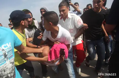 Palestinian protesters carry an injured comrade during clashes with Israeli security forces next to the border fence with Israel, at the Erez crossing in the northern Gaza strip, on October 13, 2015. A wave of stabbings...