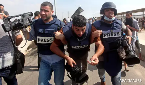 Palestinian journalists help an injured cameraman during clashes between Palestinian protesters and Israeli security forces at the Erez crossing in the northern Gaza strip, on October 13, 2015. A wave of stabbings that h...
