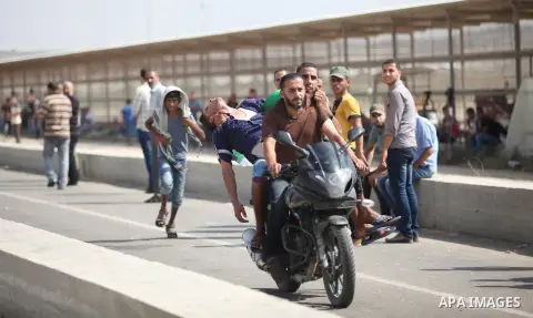 Palestinian protesters carry an injured comrade on a motorcycle during clashes with Israeli security forces next to the border fence with Israel, at the Erez crossing in the northern Gaza strip, on October 13, 2015. A wa...