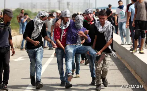 Palestinian protesters carry an injured comrade during clashes with Israeli security forces next to the border fence with Israel, at the Erez crossing in the northern Gaza strip, on October 13, 2015. A wave of stabbings...