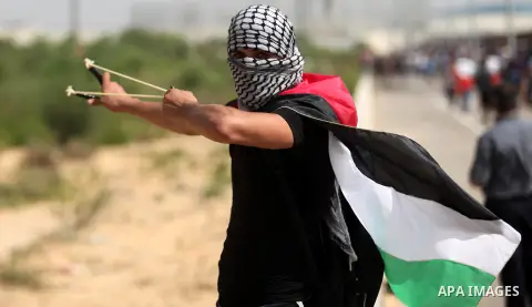 A Palestinian protester uses a sling shot to throw stones during clashes with Israeli security forces next to the border fence with Israel, at the Erez crossing in the northern Gaza strip, on October 13, 2015. A wave of...