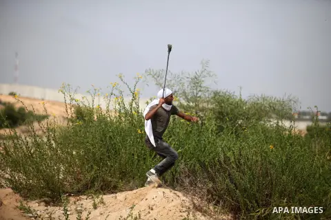 A Palestinian protester uses a sling shot to throw stones during clashes with Israeli security forces next to the border fence with Israel, at the Erez crossing in the northern Gaza strip, on October 13, 2015. A wave of...