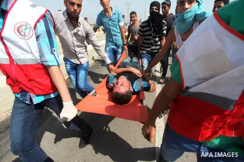Palestinian medics carry an injured protesters during clashes with Israeli security forces next to the border fence with Israel, at the Erez crossing in the northern Gaza strip, on October 13, 2015. A wave of stabbings t...