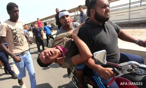 Palestinian protesters carry an injured comrade during clashes with Israeli security forces next to the border fence with Israel, at the Erez crossing in the northern Gaza strip, on October 13, 2015. A wave of stabbings...