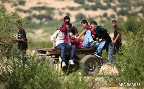 Palestinian protesters carry an injured comrade during clashes with Israeli security forces next to the border fence with Israel, at the Erez crossing in the northern Gaza strip, on October 13, 2015. A wave of stabbings...