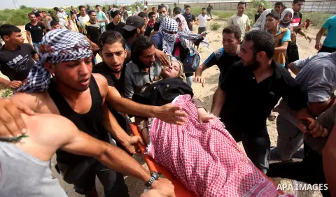 Palestinian protesters carry an injured comrade during clashes with Israeli security forces next to the border fence with Israel, at the Erez crossing in the northern Gaza strip, on October 13, 2015. A wave of stabbings...