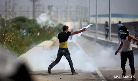 A Palestinian protester reacts from a tear gas canister fired by Israeli security forces during clashes next to the border fence with Israel, at the Erez crossing in the northern Gaza strip, on October 13, 2015. A wave o...