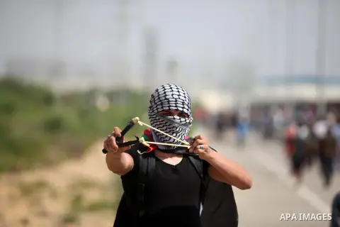A Palestinian protester uses a sling shot to throw stones during clashes with Israeli security forces next to the border fence with Israel, at the Erez crossing in the northern Gaza strip, on October 13, 2015. A wave of...