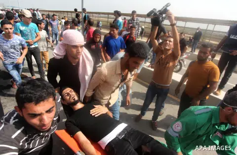 Palestinian protesters carry an injured comrade during clashes with Israeli security forces next to the border fence with Israel, at the Erez crossing in the northern Gaza strip, on October 13, 2015. A wave of stabbings...