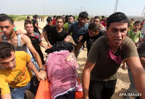 Palestinian protesters carry an injured comrade during clashes with Israeli security forces next to the border fence with Israel, at the Erez crossing in the northern Gaza strip, on October 13, 2015. A wave of stabbings...