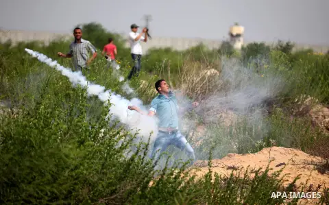 A Palestinian protester throws back a tear gas canister during clashes with Israeli security forces next to the border fence with Israel, at the Erez crossing in the northern Gaza strip, on October 13, 2015. A wave of st...