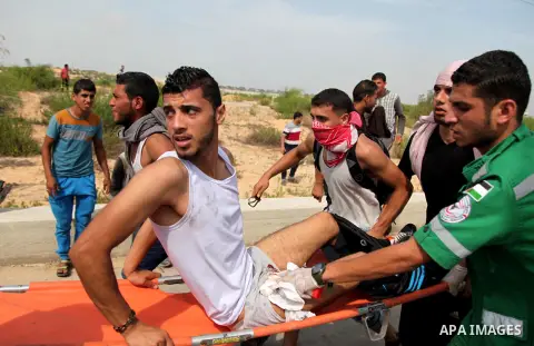 Palestinian medics carry an injured protesters during clashes with Israeli security forces next to the border fence with Israel, at the Erez crossing in the northern Gaza strip, on October 13, 2015. A wave of stabbings t...