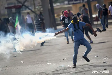 A Palestinian protester throws back a tear gas canister during clashes with Israeli security forces near the Jewish settlement of Bet El, near the West Bank city of Ramallah, on October 13, 2015. A wave of stabbings that...