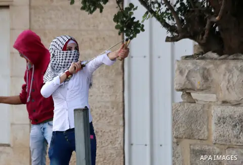 A female Palestinian protester uses a sling shot to throw stones at Israeli security forces during clashes in the West Bank city of Bethlehem, on October 13, 2015. A wave of stabbings that hit Israel, Jerusalem and the W...