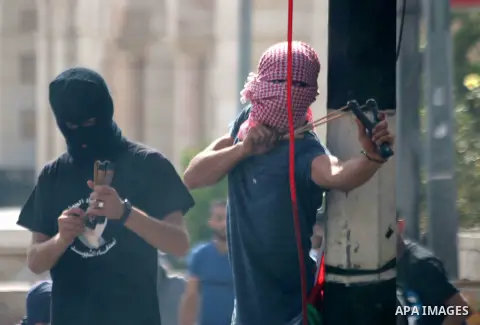 A Palestinian protester uses a sling shot to throw stones at Israeli security forces during clashes in the West Bank city of Bethlehem, on October 13, 2015. A wave of stabbings that hit Israel, Jerusalem and the West Ban...