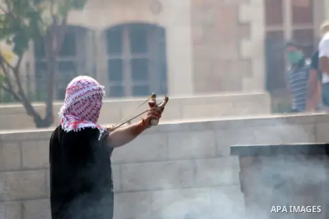 A Palestinian protester uses a sling shot to throw stones at Israeli security forces during clashes in the West Bank city of Bethlehem, on October 13, 2015. A wave of stabbings that hit Israel, Jerusalem and the West Ban...