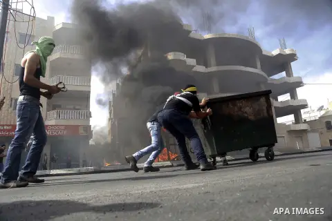 Palestinian protesters take cover during clashes with Israeli security forces in the West Bank city of Bethlehem, on October 13, 2015. A wave of stabbings that hit Israel, Jerusalem and the West Bank this month along wit...