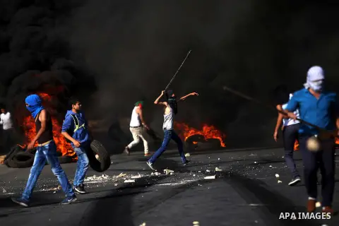 A Palestinian protester uses a sling shot to throw stones at Israeli security forces during clashes near the Jewish settlement of Bet El, near the West Bank city of Ramallah, on October 14, 2015. Seven Israelis and 30 Pa...