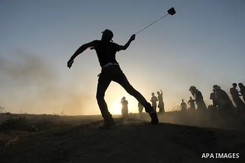 A masked Palestinian protester hurls a stone towards Israeli troops during clashes near a border fence between Israel and the Gaza Strip on October 14, 2015 east of Bureij in central Gaza. The outbreak of violence betwee...
