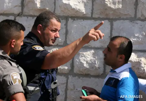 An Israeli policeman blocks a Palestinian worshiper from enter the al-Aqsa mosque compound before the Friday prayers on the streets of the Wadi al-Joz neighbourhood in east Jerusalem following restrictions by Israeli pol...